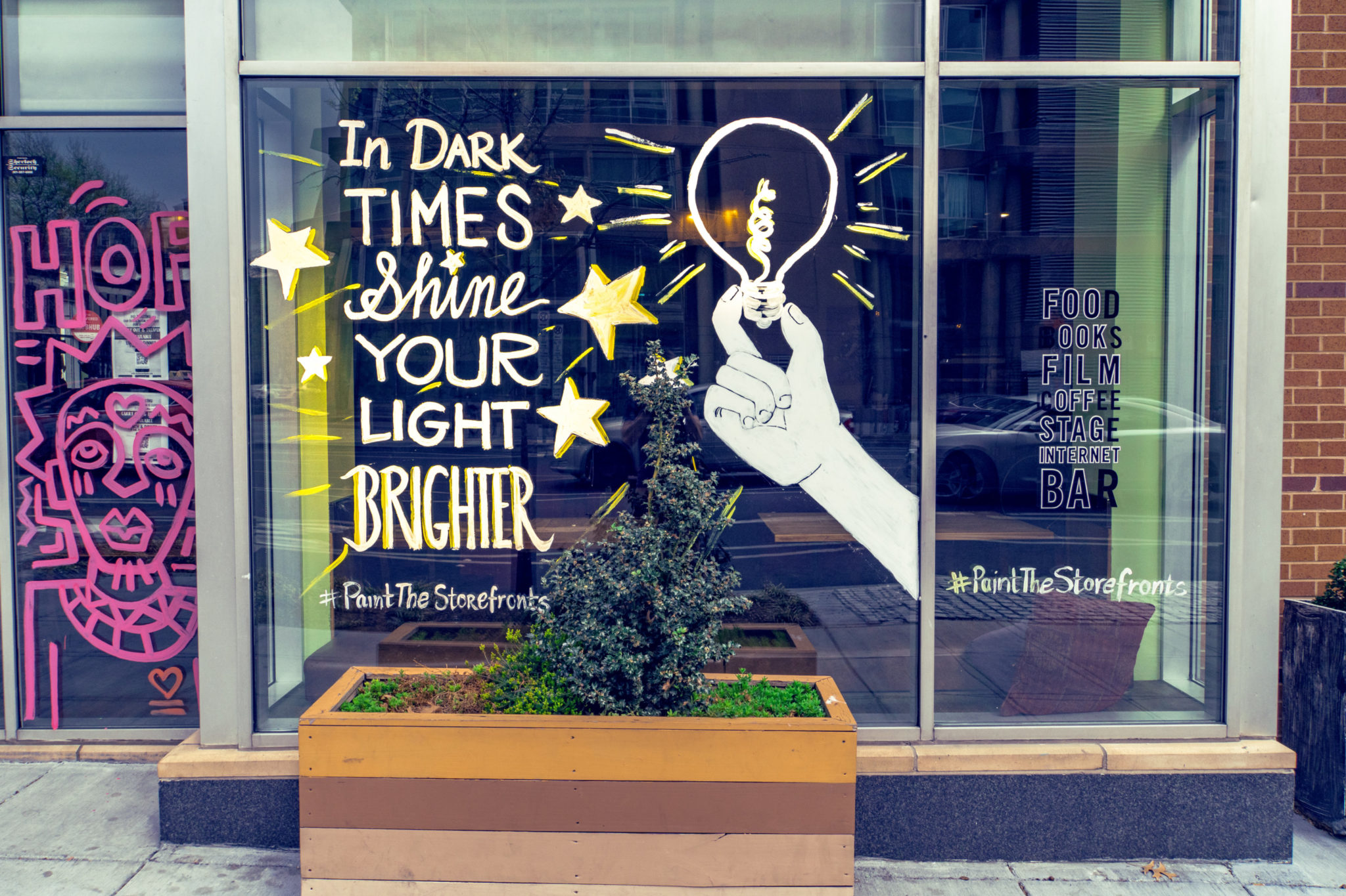 window at busboys and poets in washington reads "in dark times, shine your light brighter"