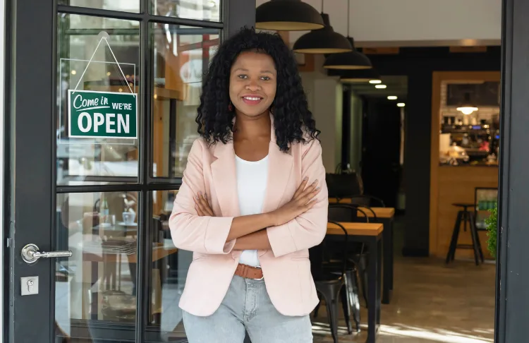 Customer referral program - women stands in front of a shop with an open sign.