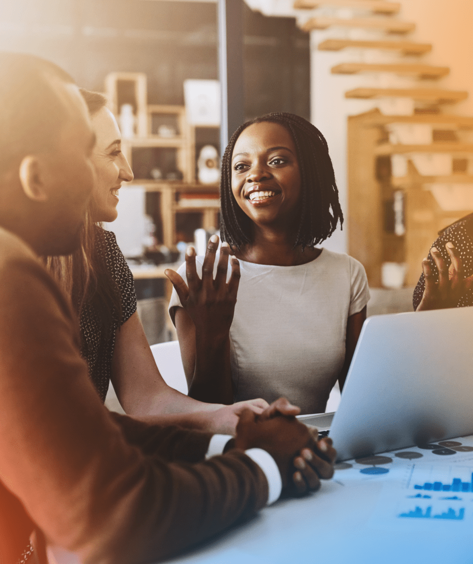 Woman speaking to two team members while on her laptop