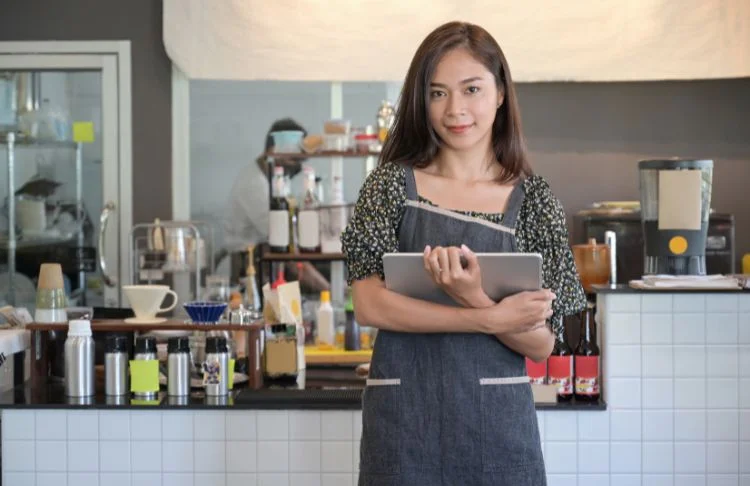 Lead generation examples - woman holds laptop in front of a coffee counter.