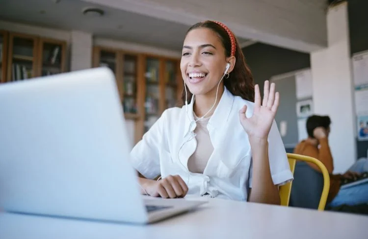 How to host a webinar - woman waves to laptop camera.