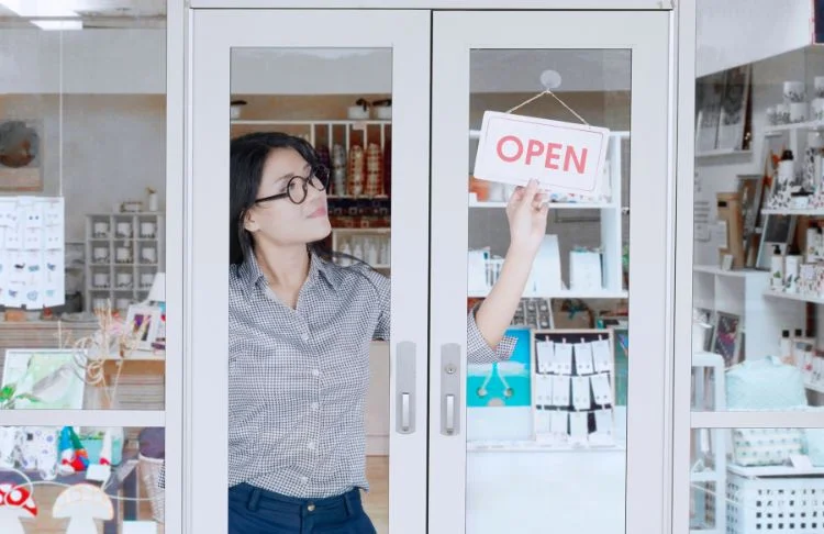 Offline marketing ideas - Woman turns open sign in shop window.