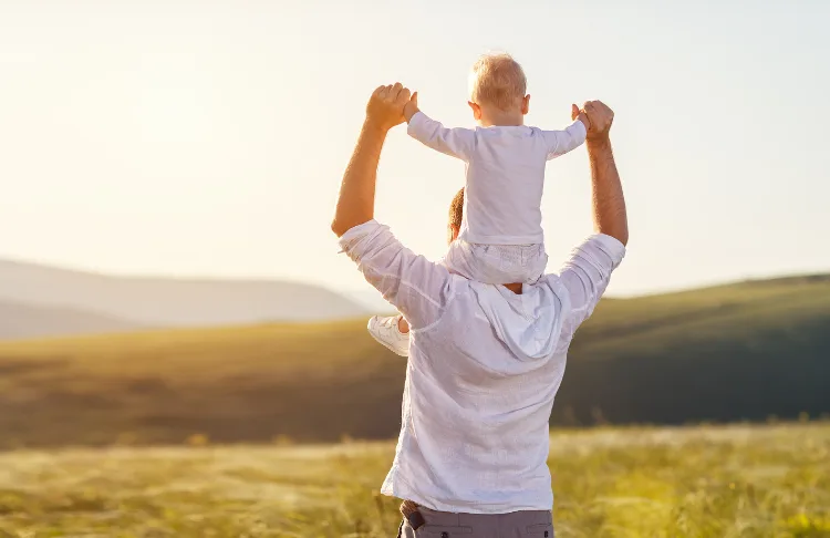 fathers day slogans - view of father holding son on shoulders looking into green space