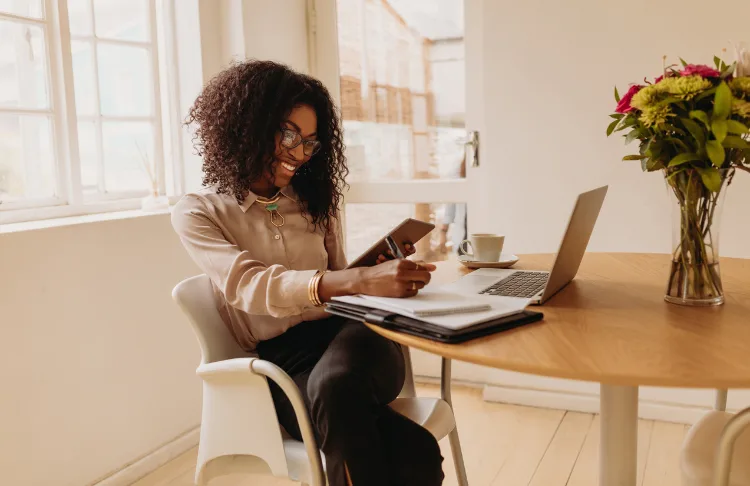 Email marketing checklist - woman looks at tablet and takes notes.