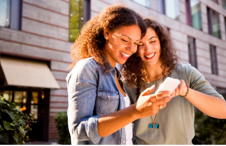 Tiktok hashtags - two women look at a cellphone.