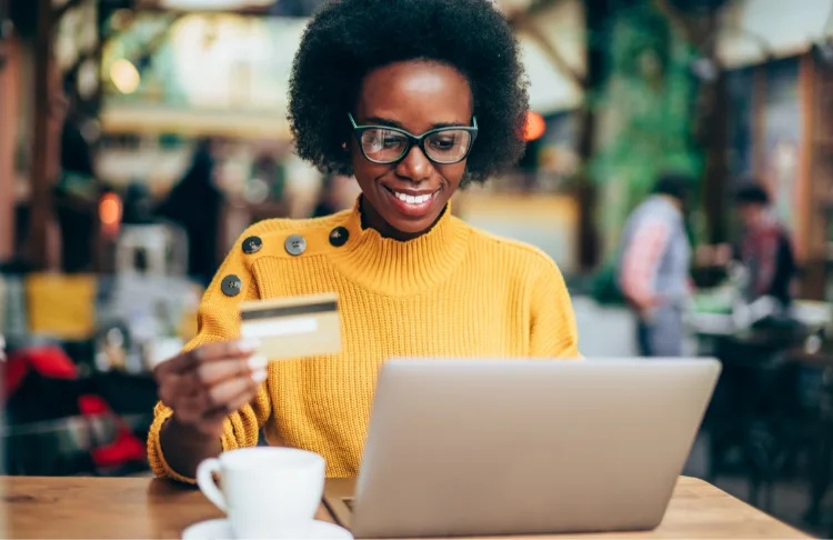 How to sell on TikTok - Woman holding a credit card while looking at her laptop.