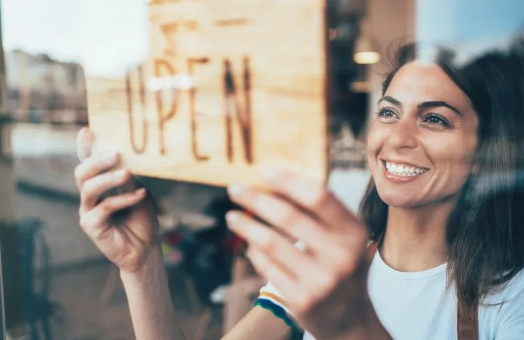 woman holding open sign at new business location