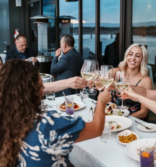 group of women cheers with wine glasses at dinner